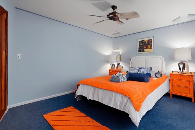 a 10 by 11 foot old bed room with blue grey criss cross patterned walls, white ceiling, navy blue carpet, a small bed, desk, two wooden wardrobes, an old TV, and a ceiling fan gives off a dim orange light at night time